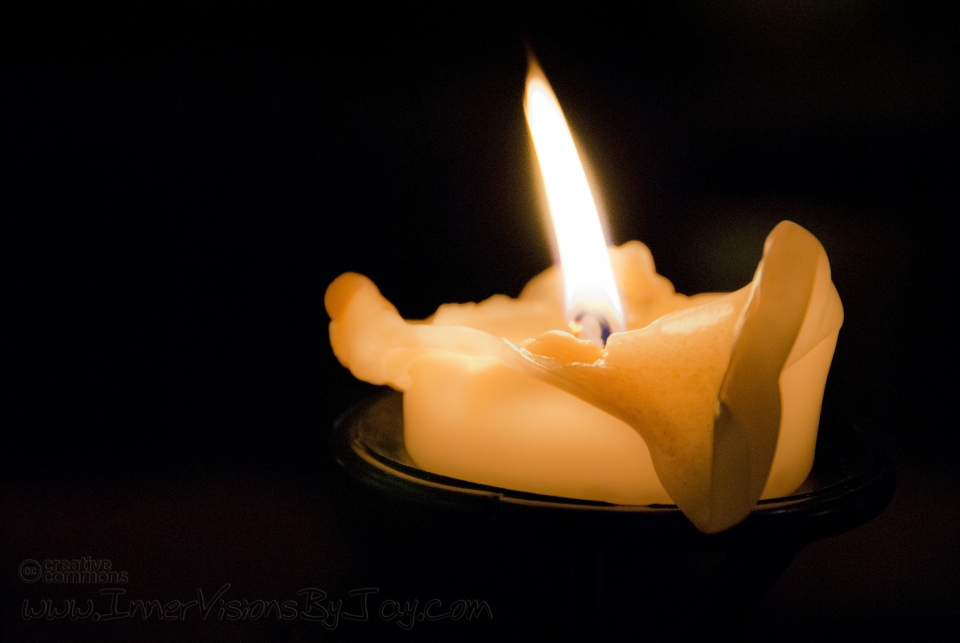 Candle burning down against black background