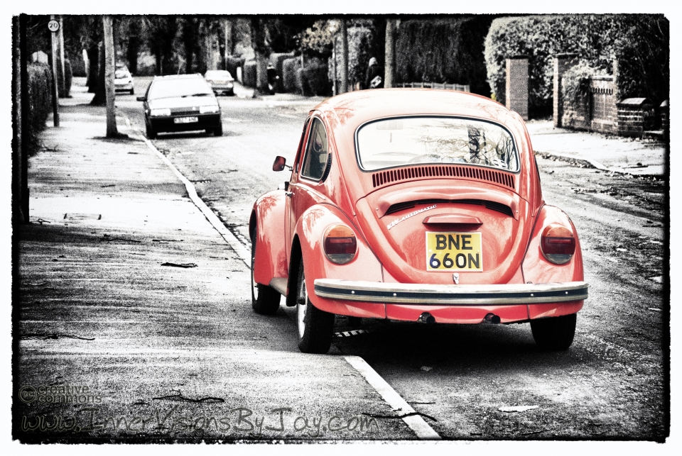 Selective color red volkswagen beetle parked on winter curb