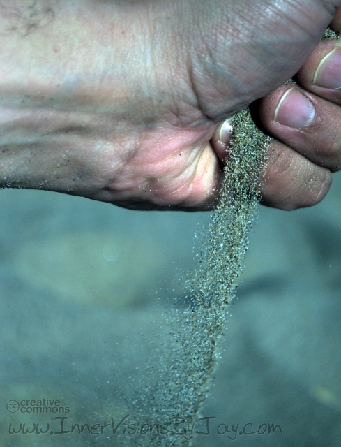 Sand slipping through a hand over a green background